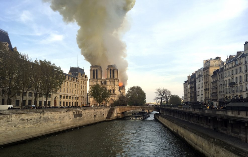 From a distance, the smoke can be seen billowing up from behind a church.